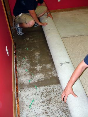 Saluda water damaged carpet being removed by two men.
